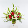 Red roses and white lilies in a glass vase with tall green accents