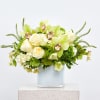 Green and white floral arrangement in a glass vase