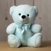 Light blue teddy bear with a satin bow sitting on a table