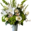 White lilies and orchids in a tall gray vase with green hydrangeas