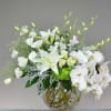 White floral arrangement in a clear glass vase with orchids and lilies