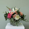 A mix of pale dahlias, pink roses, and peach spray roses make