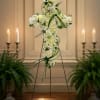 A serene all-white cross covered in cream and white roses, chrysanthemums, daisies