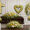 Sympathy floral set with yellow and white arrangements around a casket