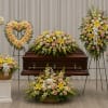 Funeral casket surrounded by pastel floral sprays and wreaths