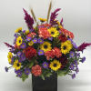 A bright mix of fresh, fall toned flowers designed in a wooden
