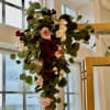 Tall floral arrangement with pink and white roses and dark burgundy blooms
