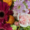 Close-up bouquet of pink roses, magenta daisies, and orange blooms