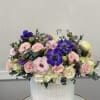 Mixed pink and purple flowers arranged in a white textured vase