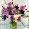 Pink and purple bouquet with roses, dahlias, and white hydrangeas in a glass vase