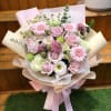 Bouquet of pink roses, gerbera daisies, and mixed blooms wrapped in pastel paper