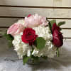 Pink and red roses with white hydrangeas in a glass vase