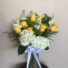 Yellow roses and white hydrangeas in a glass vase with a white ribbon
