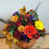 Mixed autumn bouquet in a pumpkin-shaped container with bright flowers