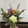 Mixed bouquet in a glass vase with pink roses and a green hydrangea bloom