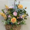 A woven wall hanger basket filled with pastel artificial flowers. 