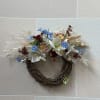 A stick wreath with white and cream artificial and dried flowers with