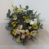 An artificial eucalyptus wreath with a birds nest and pops of purple