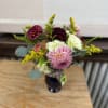 Mixed bouquet with pink, white, and burgundy blooms in a dark vase
