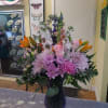 Mixed bouquet of pink, purple, and orange flowers in a dark vase