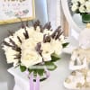 White rose bouquet in a striped vase with purple accents