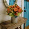 Orange roses and green hydrangeas in a ribbed metal vase