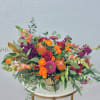 Mixed bouquet of roses, snapdragons, and protea in a silver vase