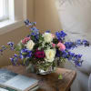 Bouquet of pink and white roses with blue flowers in a glass vase