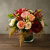 Mixed bouquet of roses, chrysanthemums, and lilies in a glass vase