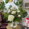 White roses and hydrangea in a glass vase with a ribbon