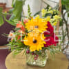 Yellow gerberas and red roses in a square glass vase