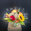 Mixed bouquet with roses, lilies, sunflowers, and alstroemeria in a glass vase