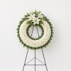 White floral wreath on a black easel with lilies and daisies