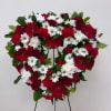 Heart-shaped floral wreath with red and white flowers on a stand