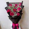 Bouquet of hot pink roses with baby's breath in black wrap and a pink ribbon