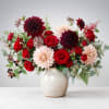 Bouquet of red and blush flowers in a speckled ceramic vase