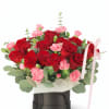 Red roses and pink carnations in a black hatbox with a pink ribbon