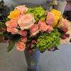 Pink and yellow roses with green hydrangeas in a tall vase