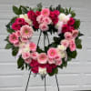 A heart-shaped wreath built from lush clusters of pink and white roses