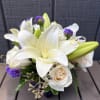 White lilies and cream roses arranged with purple accents in a vase