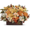 Low centerpiece of orange roses, yellow lilies, and white blooms in a dark rectangular container