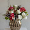 A festive winter arrangement featuring white roses, red alstroemeria, and frosted pinecones