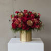 Red rose bouquet in a gold vase with pinecone accents