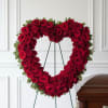 Heart-shaped red rose funeral spray on a stand