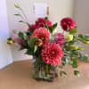 Pink and coral flowers arranged in a clear glass vase