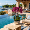 Potted purple orchids in a reflective silver bowl beside a pool
