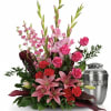 Pink lilies and roses arranged beside a silver urn