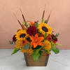 Autumn flower arrangement with sunflowers, lilies, and mums in a wooden planter