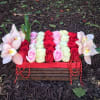Rectangular floral arrangement with red, pink, and white roses and pale orchids in a wooden box