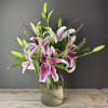 Pink and white lilies arranged in a glass vase